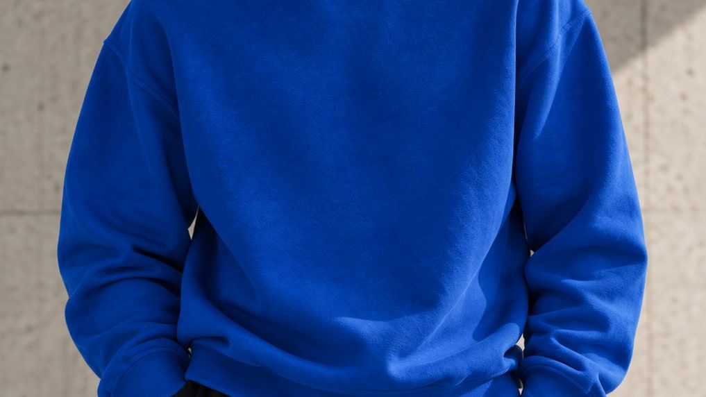 Person wearing a bright blue sweatshirt against a concrete wall